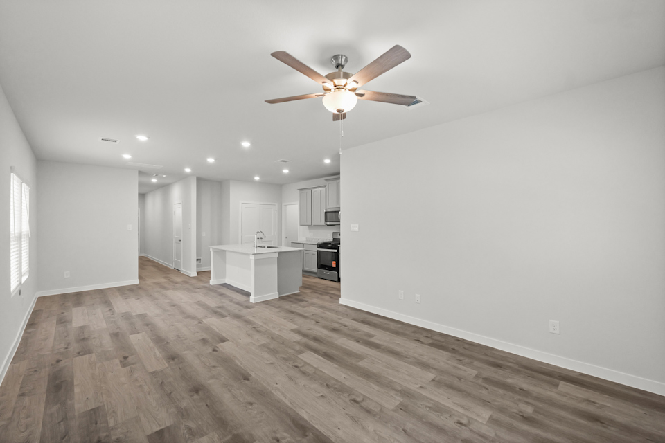 A large empty room with a ceiling fan and a wood floor.