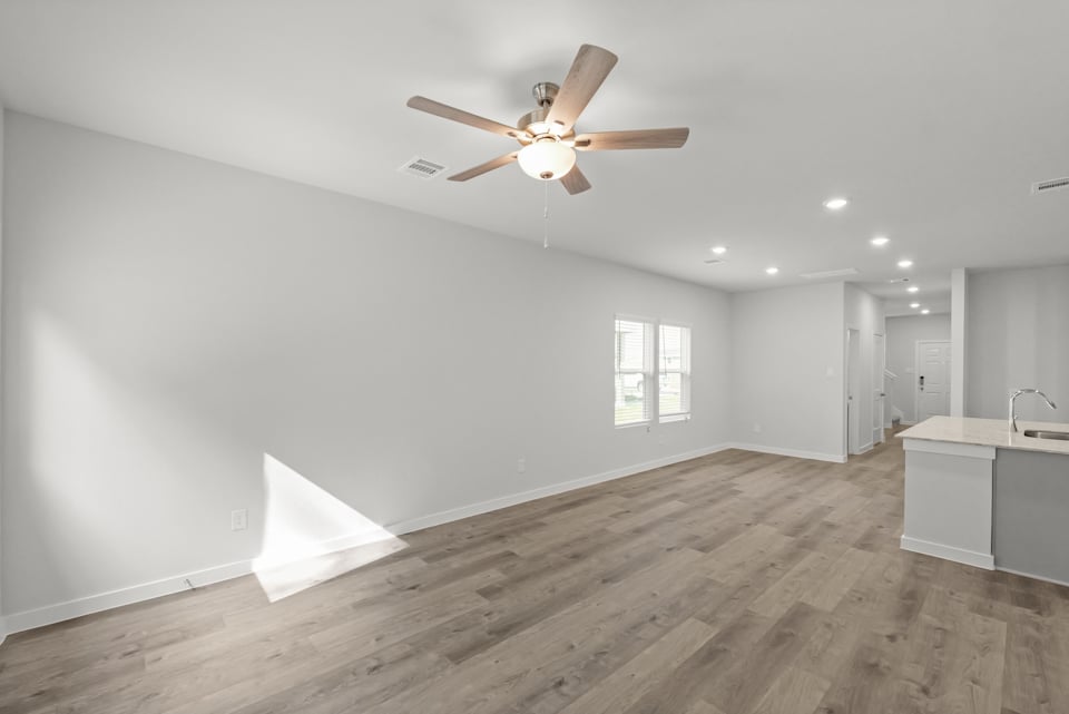 A room with a ceiling fan and a wood floor.