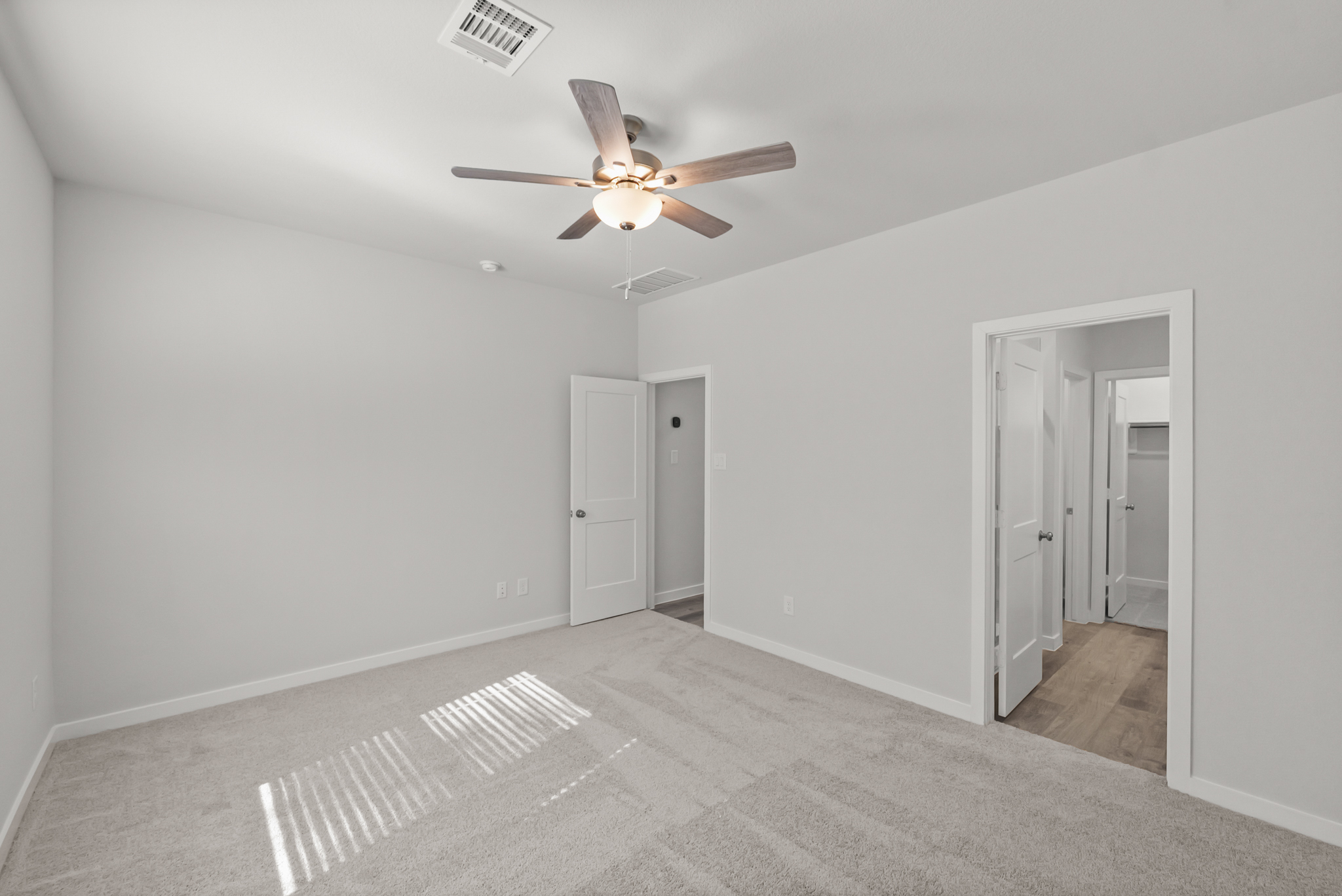 A room with a ceiling fan and white walls.