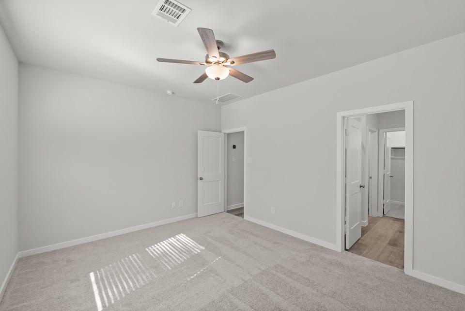 A room with a ceiling fan and white walls.