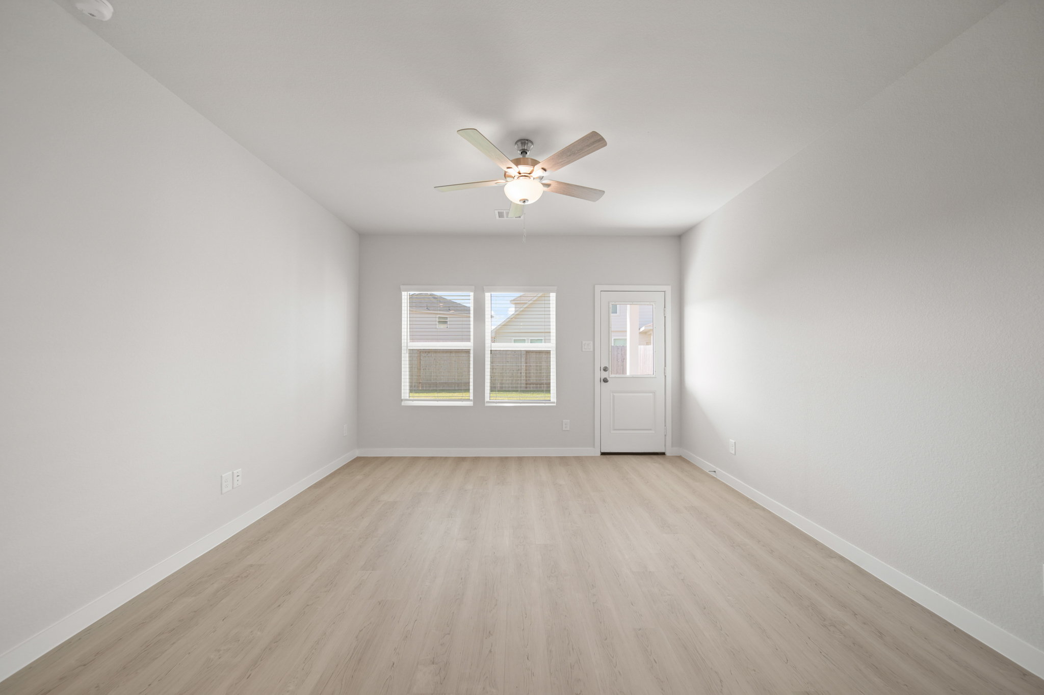 A room with a ceiling fan and a wood floor.