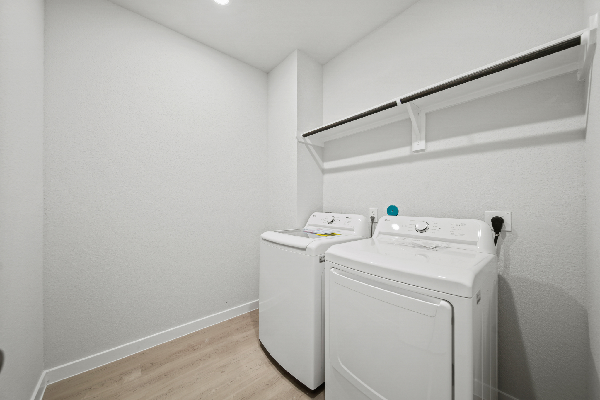 A white laundry room with a white shelf and a white wall.