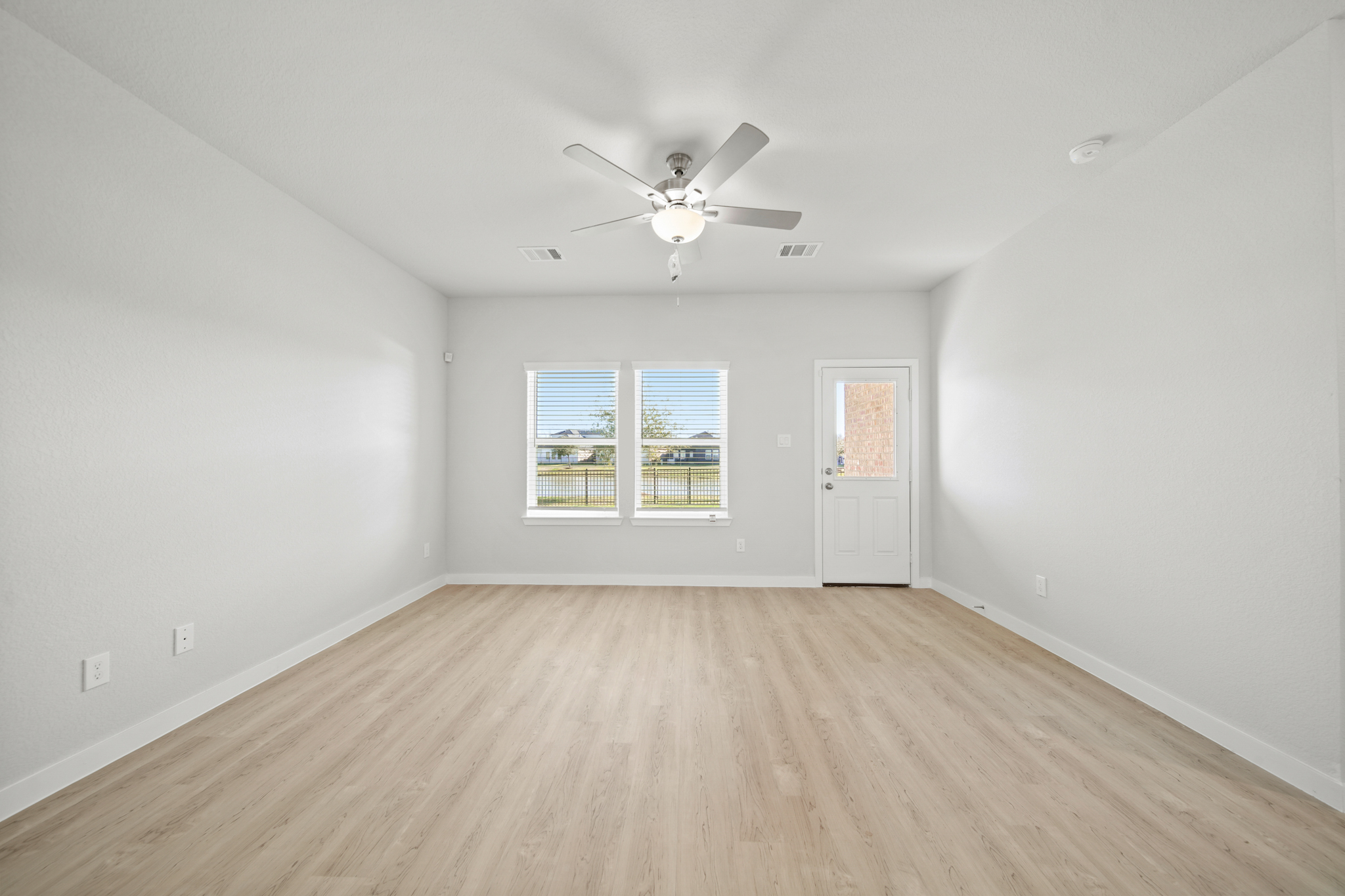 A room with a ceiling fan and a wood floor.
