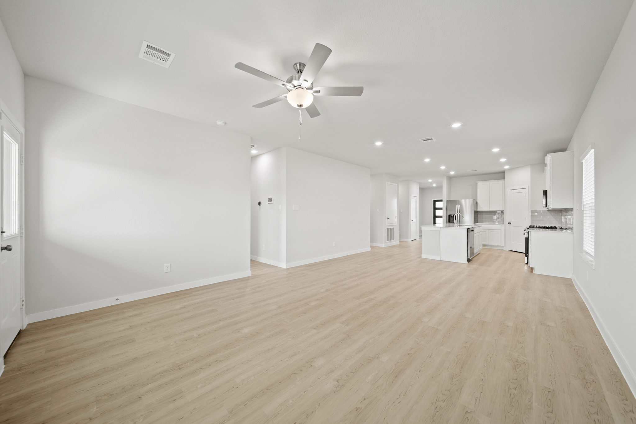 A large empty room with a ceiling fan and a wood floor.