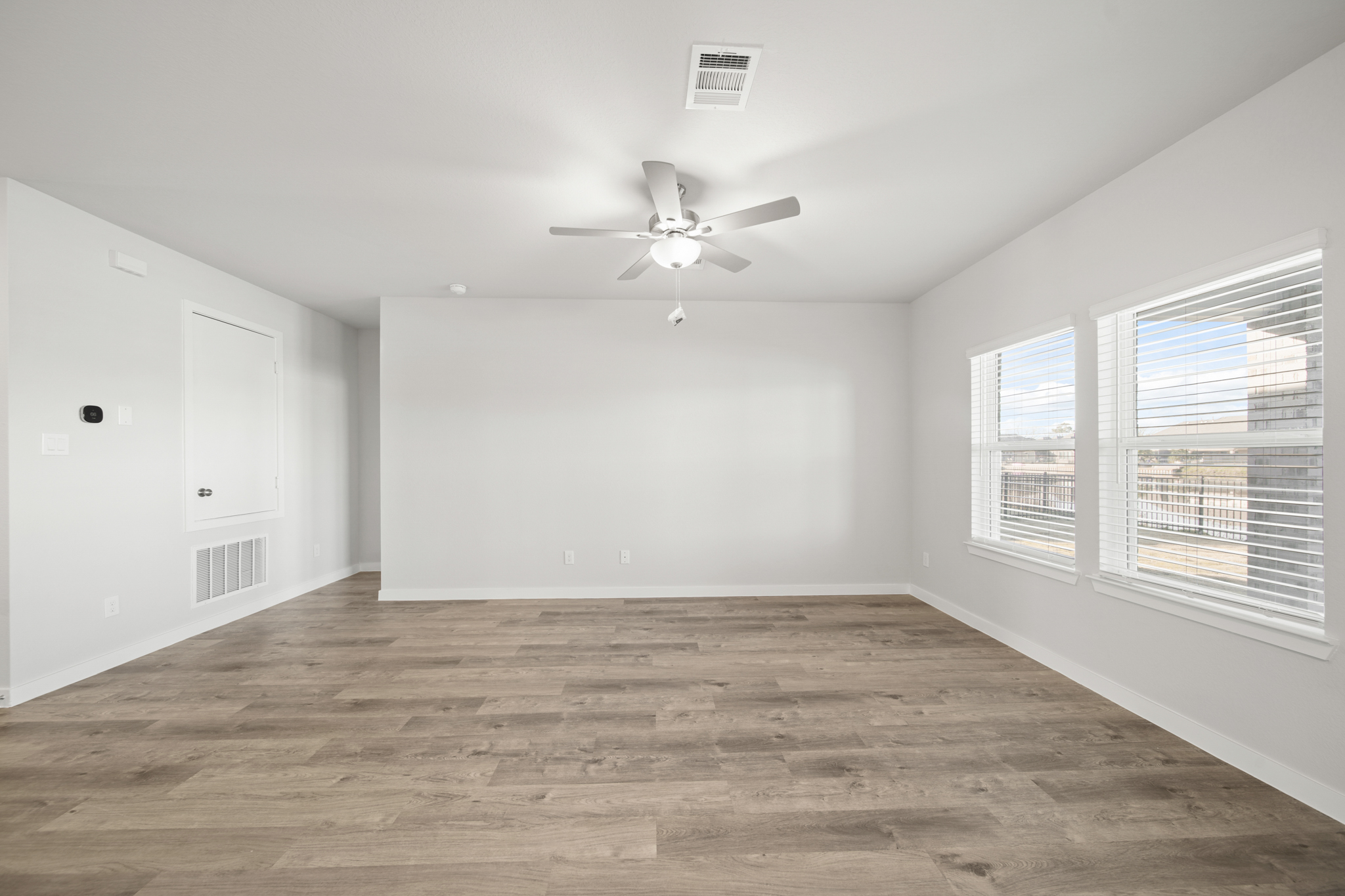 A room with a ceiling fan and a wood floor.