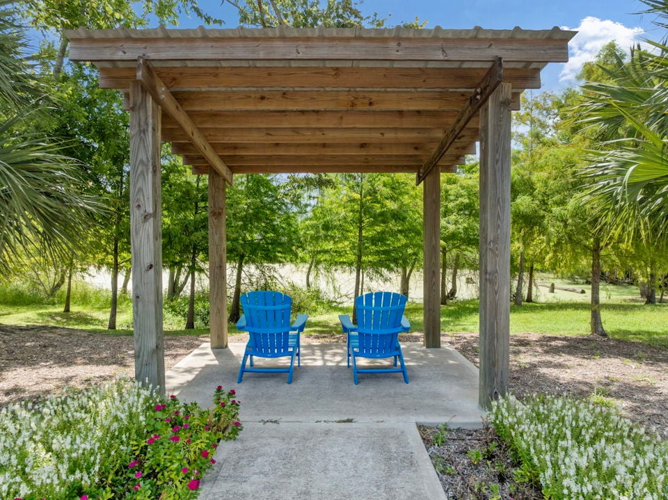 A wood gazebo with blue chairs.