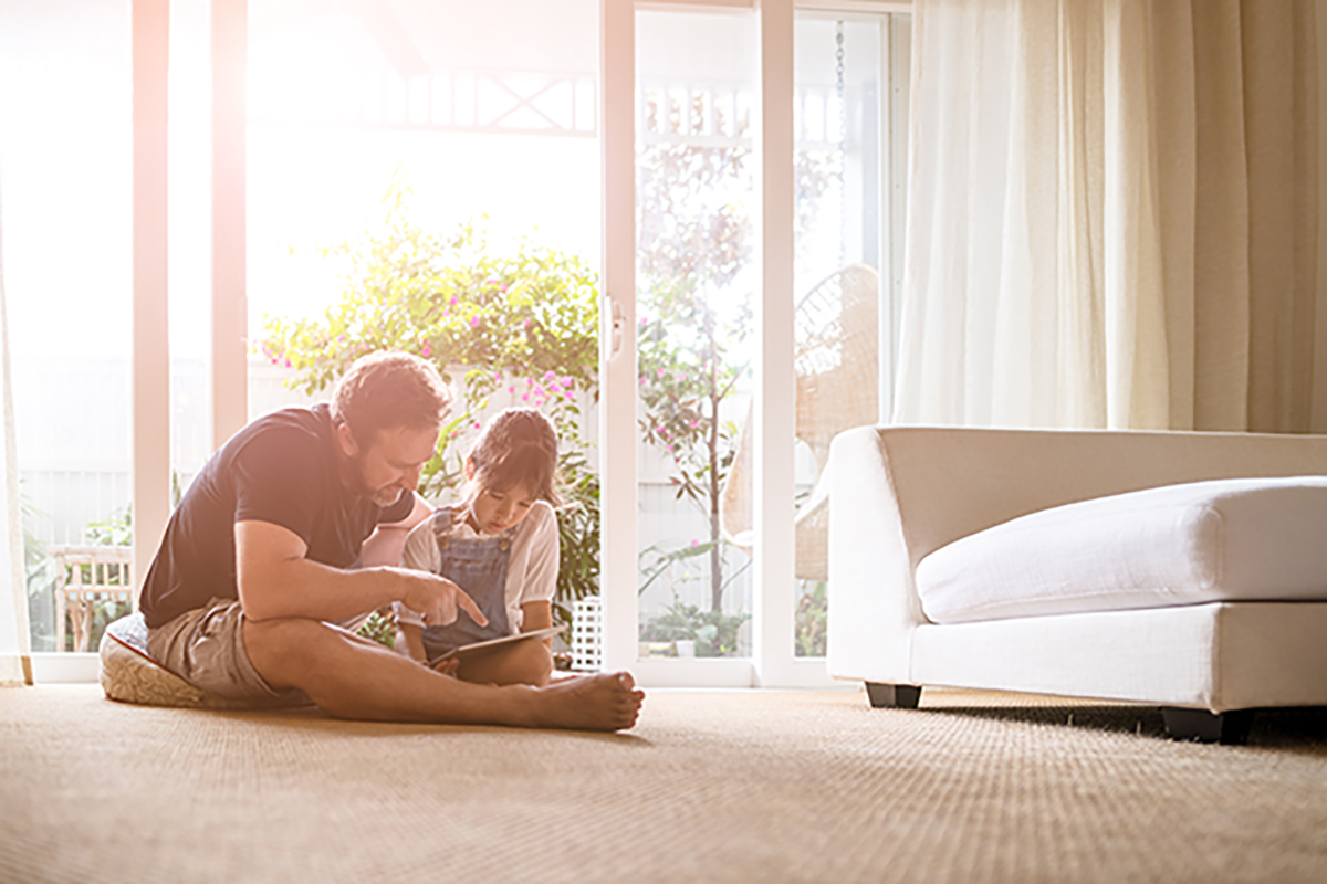 A person and a child sitting on the floor reading a book.