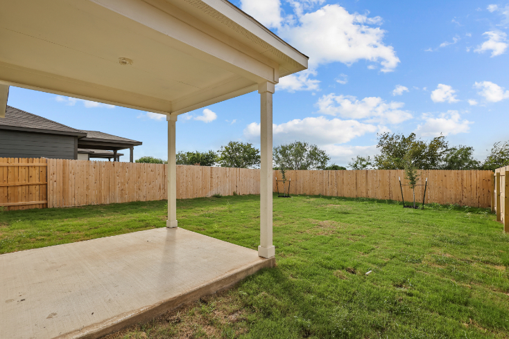 A fenced in yard with a covered area and a wood structure.