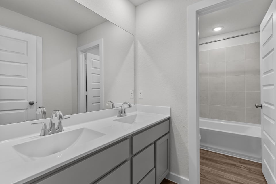 A bathroom with a tub sink and a mirror.