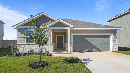 A house with a garage and a tree in the front.