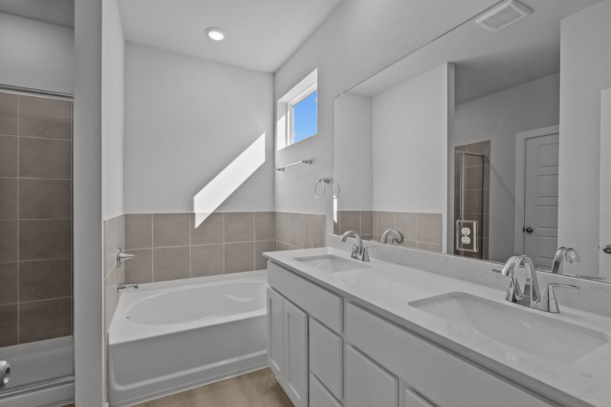 A bathroom with a tub sink and mirror.