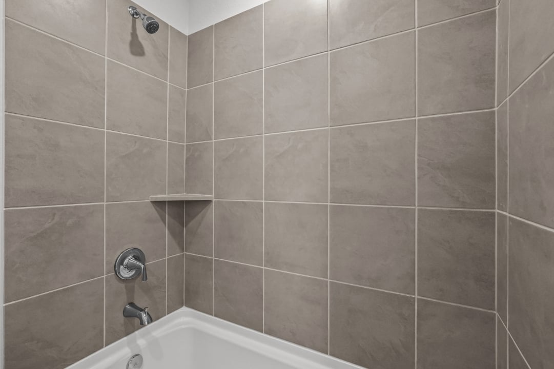 A bathroom with a bathtub and tile walls.
