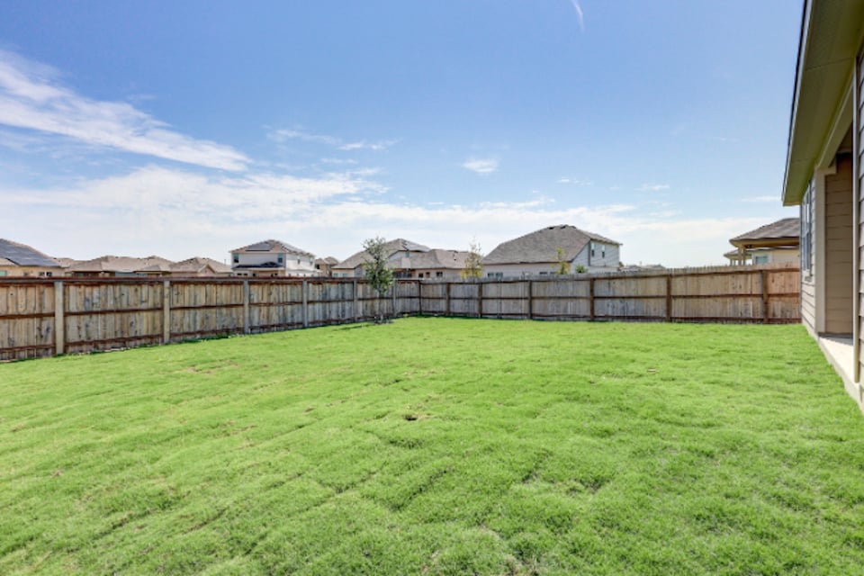 A fenced in yard with houses in the background.