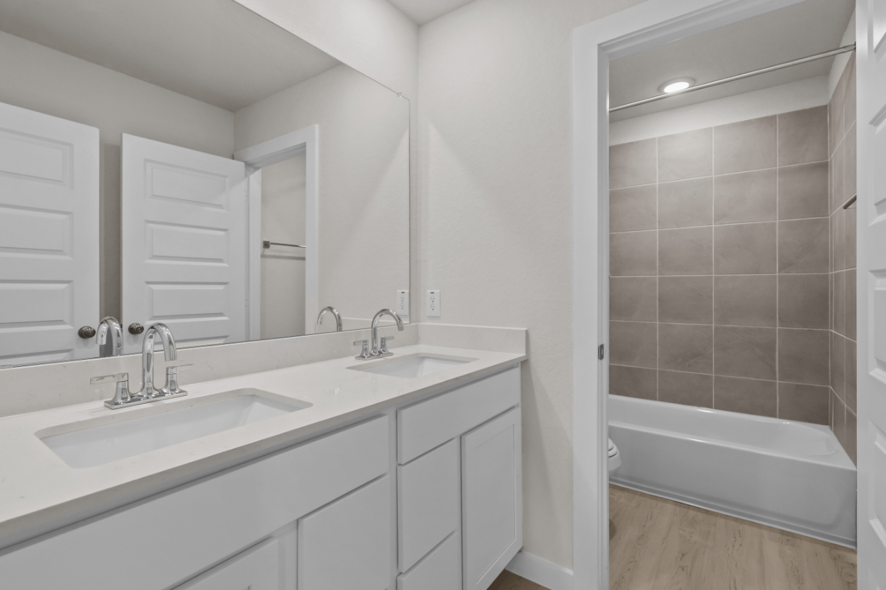 A bathroom with a tub sink and mirror.