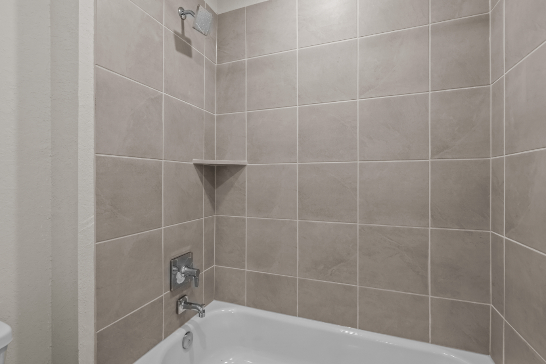 A bathtub with a tile wall.