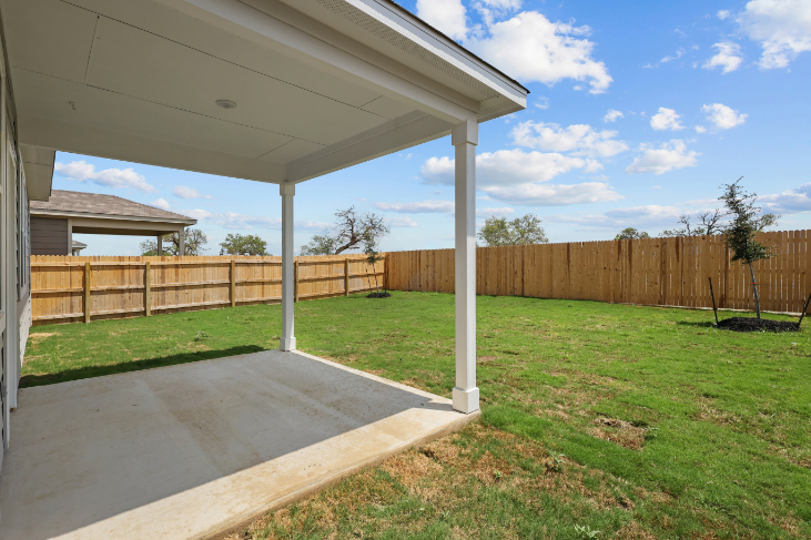 A fenced in yard with a covered area and a wood fence.