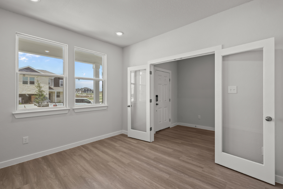 A room with white walls and a wood floor with a window and a wood floor.