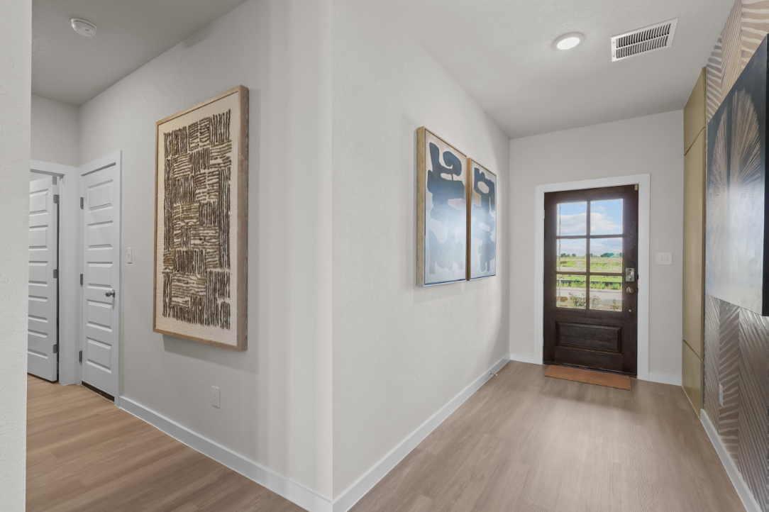 A room with a wood floor and white walls with art on the wall.