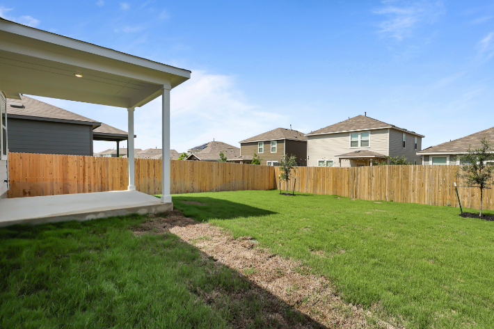 A backyard with a fence and a house.