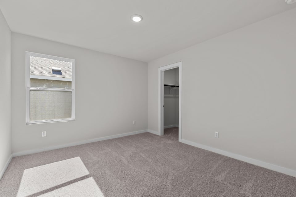 A room with a carpet and a window.