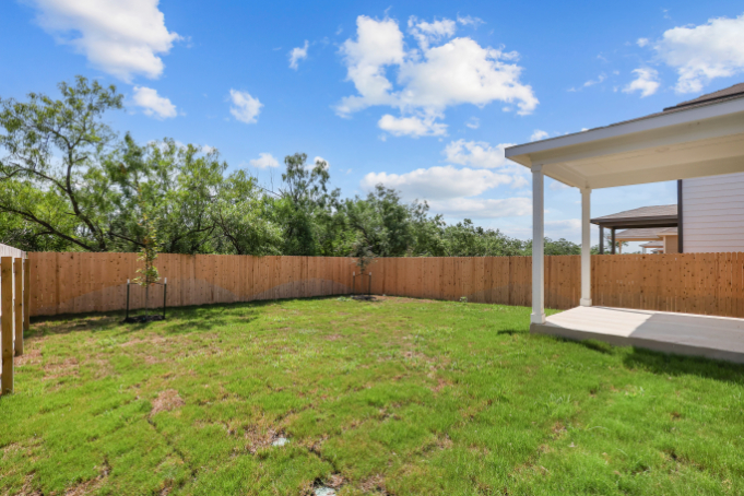 A fenced in yard with a wood fence and trees in the background.