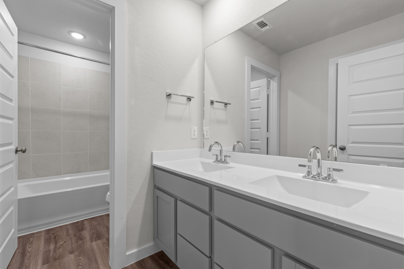 A bathroom with a tub sink and a mirror.