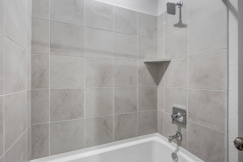 A bathtub with a tile wall.