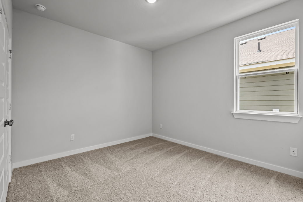 A room with a carpet and a window.