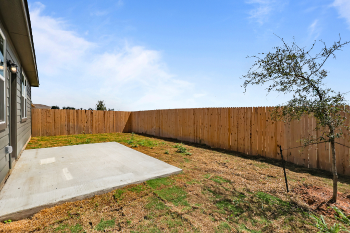 A fenced in yard with a wood fence and a tree.