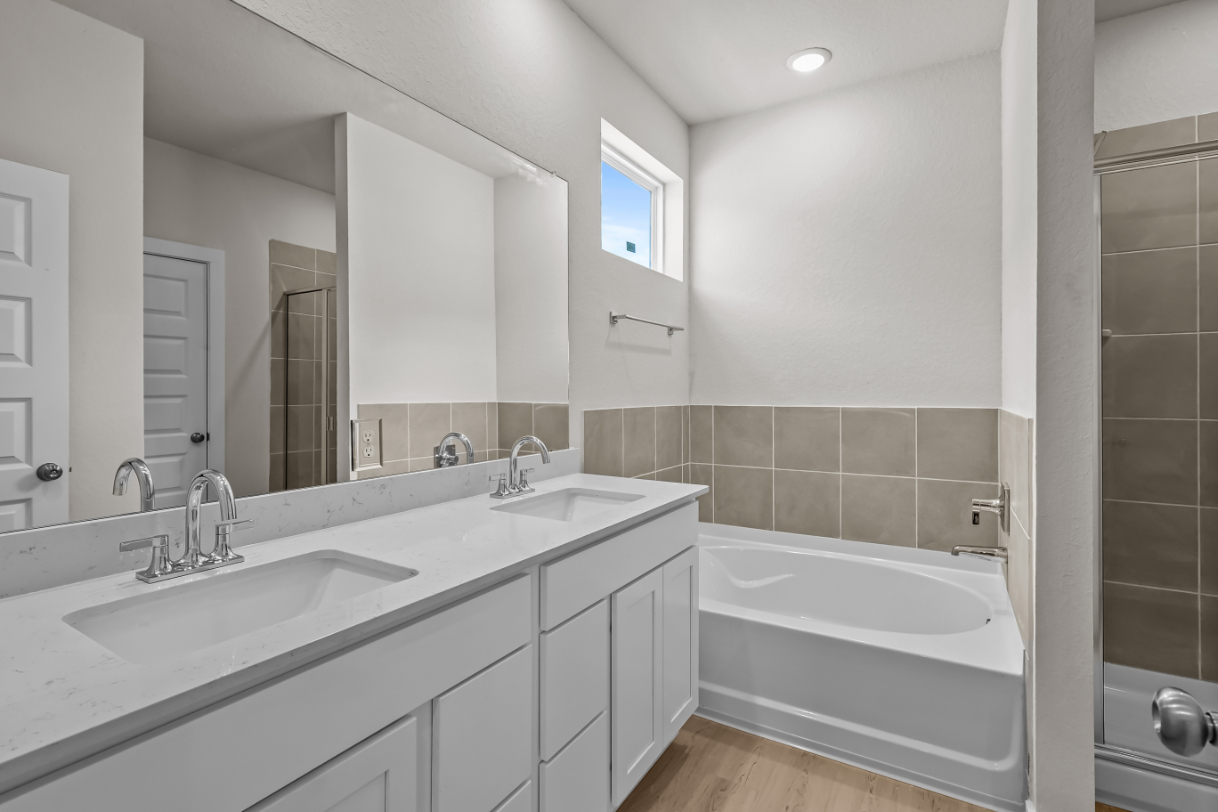 A bathroom with a tub sink and mirror.
