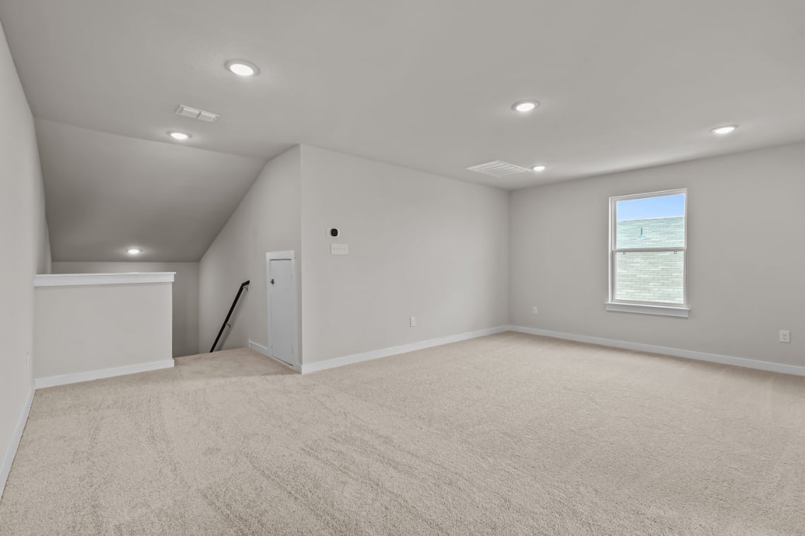A room with a carpet and a white wall.
