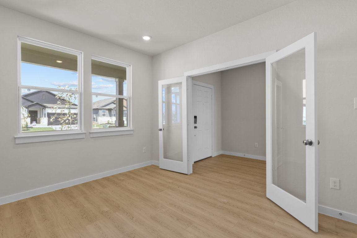 A room with white doors and a wood floor.