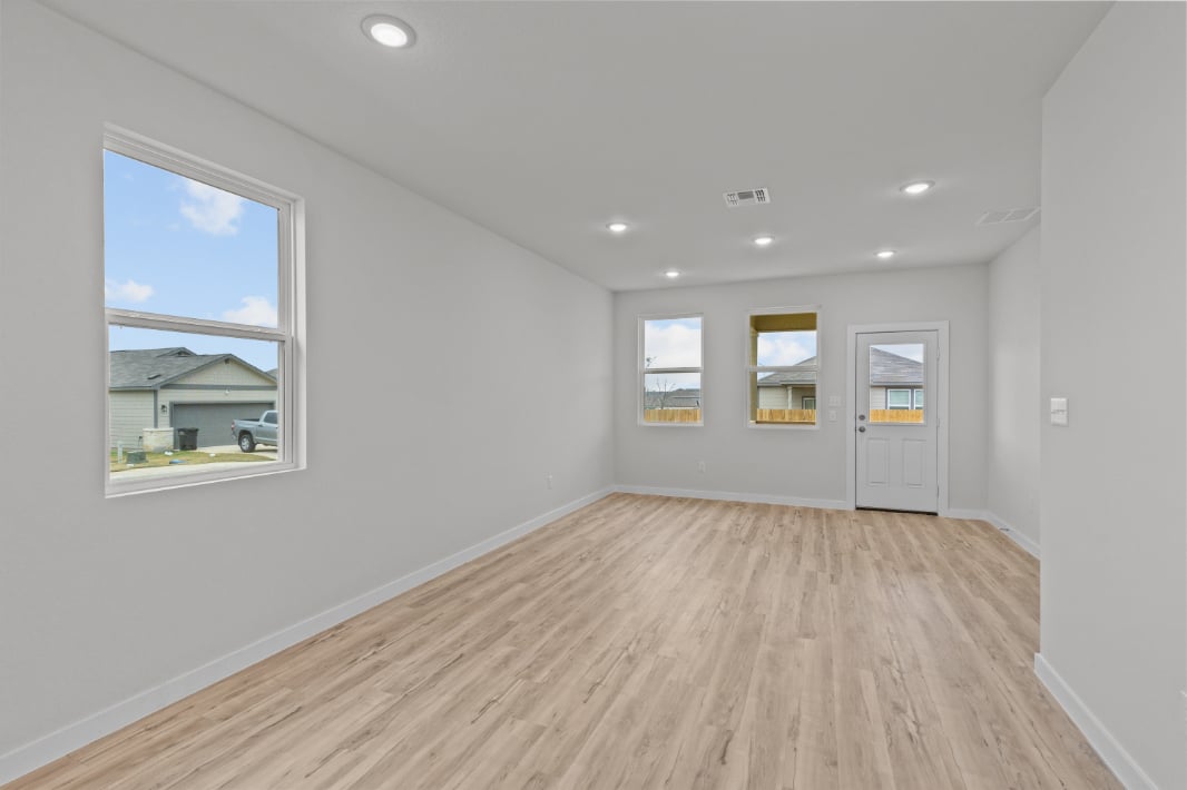 A room with a wood floor and a window with a view of the water.