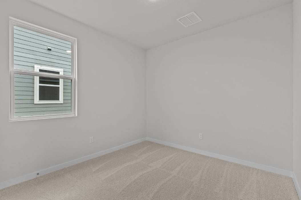 A room with a window and a rug.