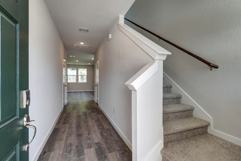 A hallway with a door and a staircase.