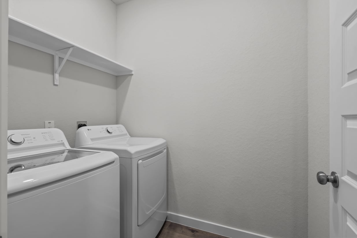 A white room with a washing machine and a dryer.