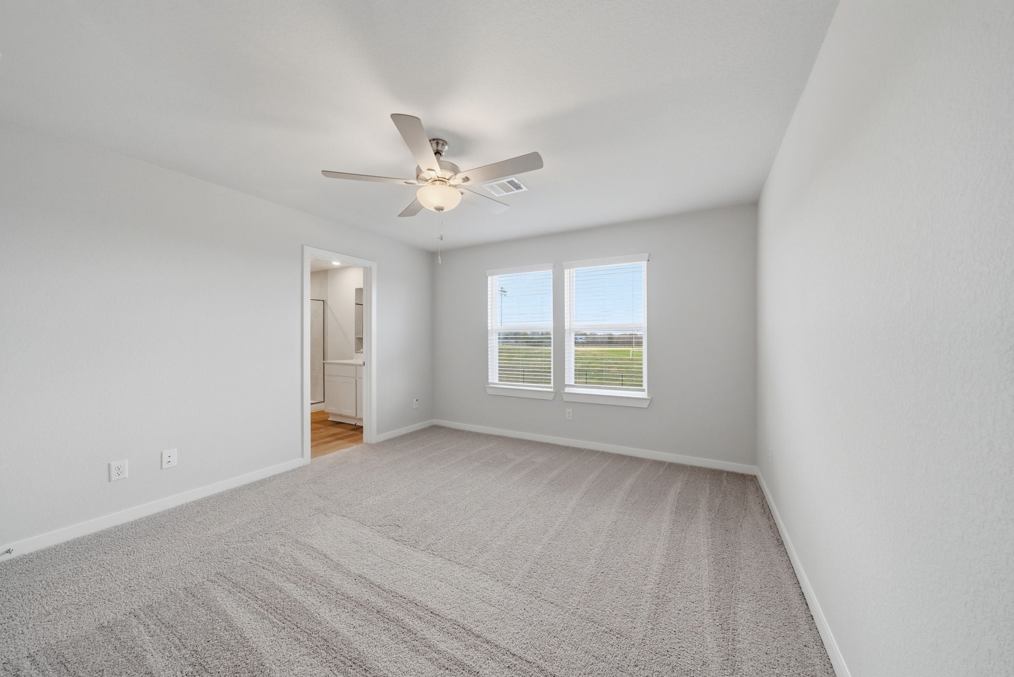 A room with a ceiling fan and a carpet.