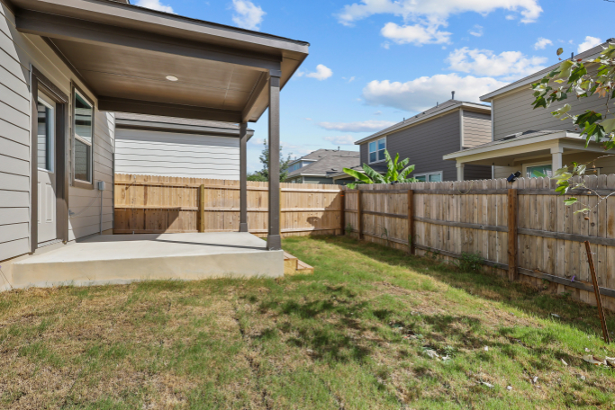 A fenced in yard with a house and a wood fence.