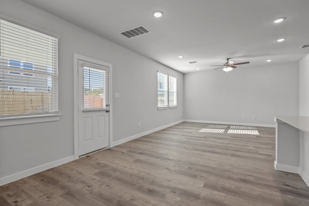 A room with a wood floor and a wood floor with a fan.