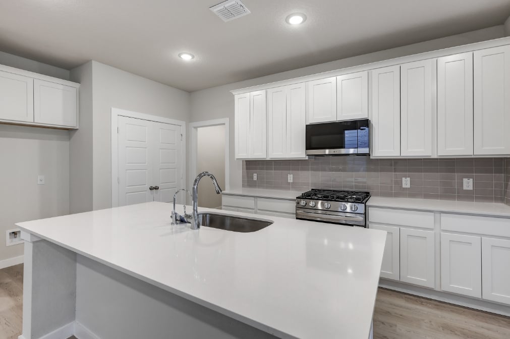 A kitchen with white cabinets.