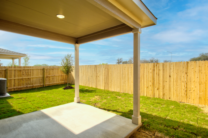 A backyard with a fence and a trampoline.