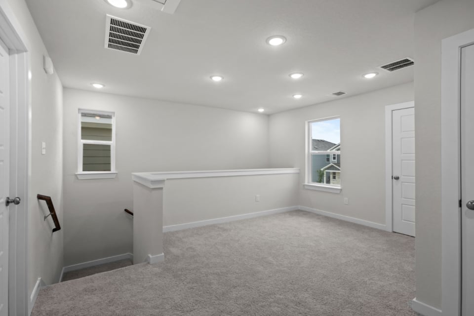 A large white room with a bathtub and a window.