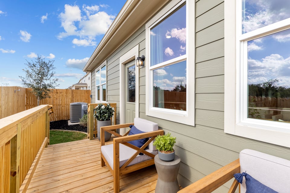A deck with a table and chairs and a window with a view of the ocean.