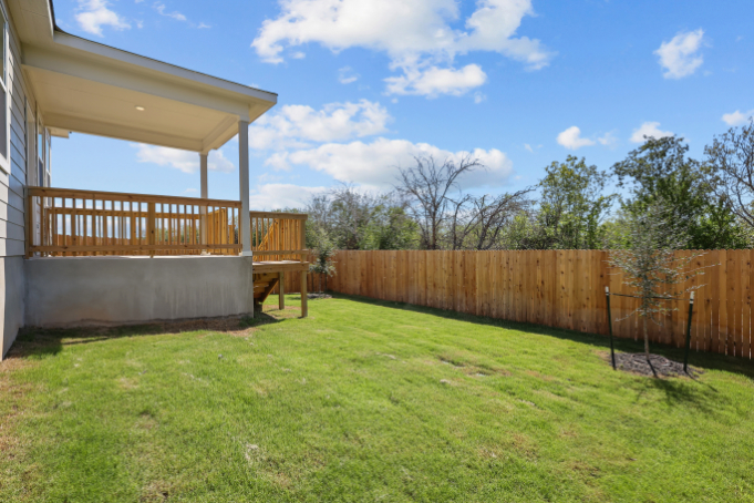 A fenced in yard with a wood gate and a wood building.