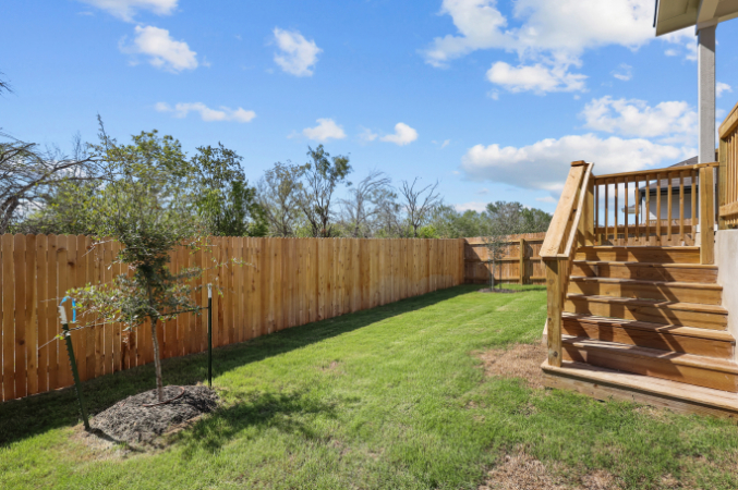 A fenced in yard with a wooden staircase and a wood fence.
