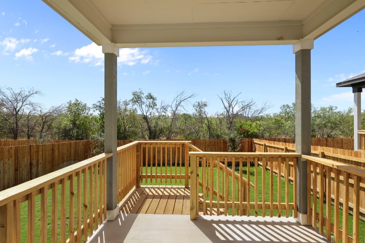 A deck with a railing and trees in the background.