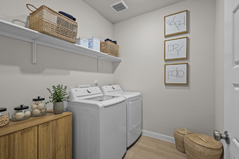 A laundry room with a white laundry machine and baskets.