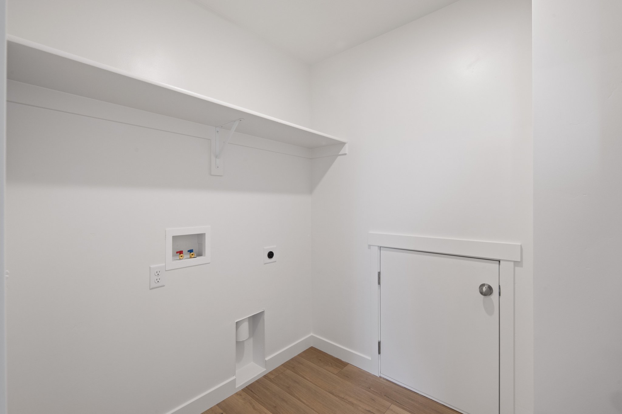 A white room with a wood floor and a white door.
