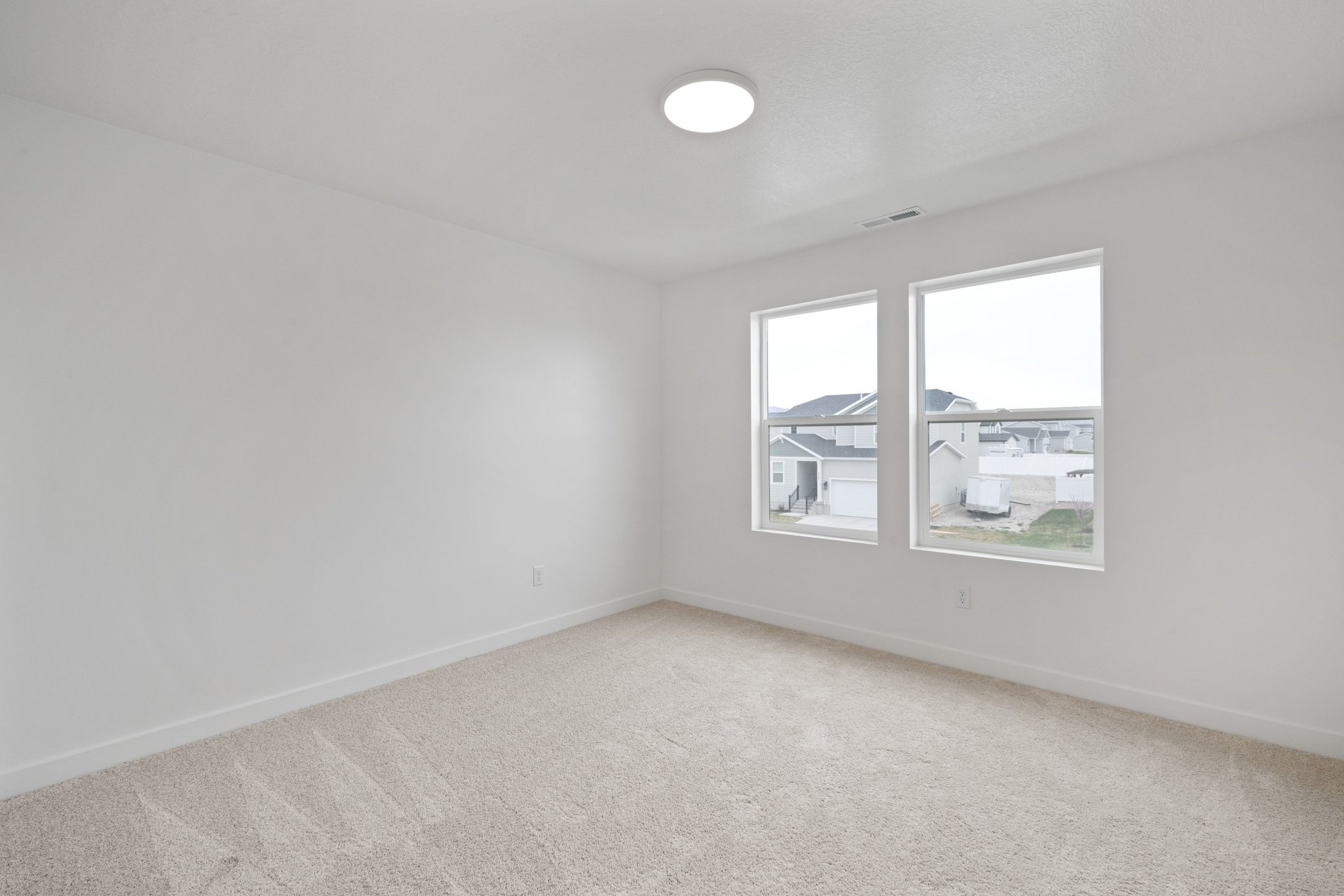 A room with a window and a light on the wall.