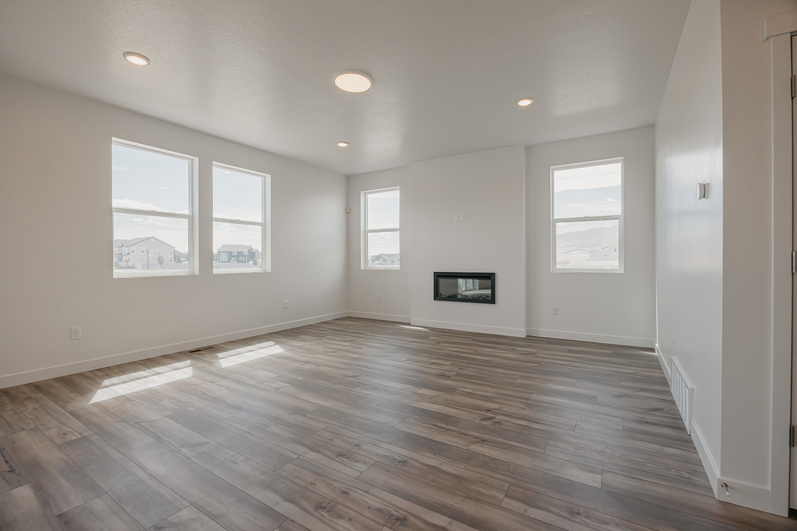 A room with a wood floor and a wood floor with a few windows.